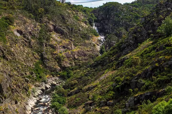 Scenic view of lush green hills and rocky terrain surrounding the 516 Arouca Suspension Bridge in Portugal.