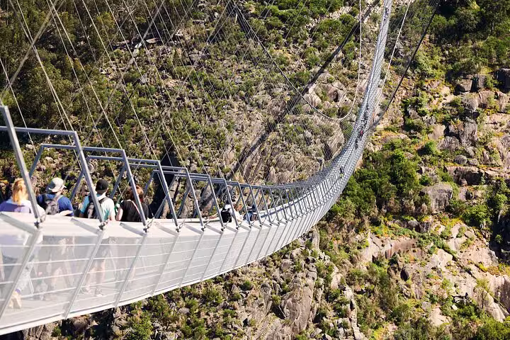 Tourists crossing the 516 Arouca Suspension Bridge with stunning views of the rocky landscape below.