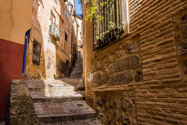 Narrow cobblestone alley with ancient stone walls on a guided medieval walking tour in Toledo Spain