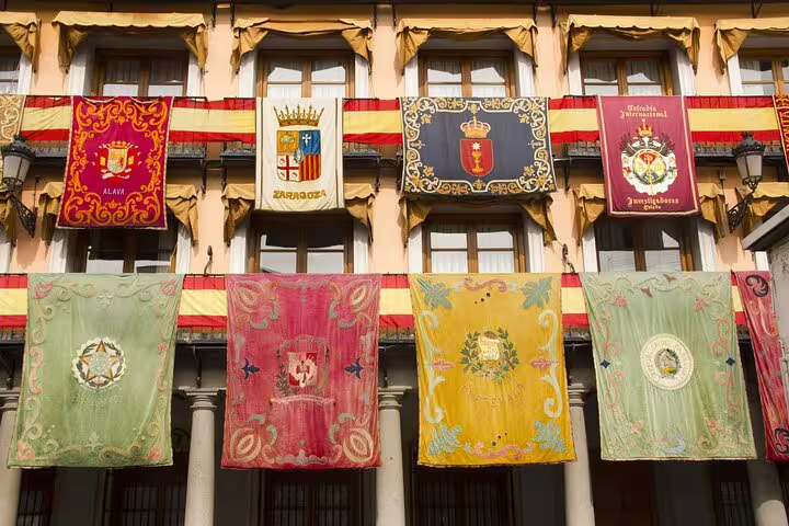 Colorful medieval heraldic banners and coat of arms displayed on historic building in Toledo Spain walking tour