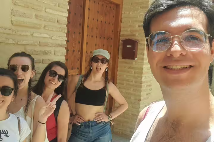 Happy group of tourists posing with guide at Toledo medieval stone building during legends walking tour