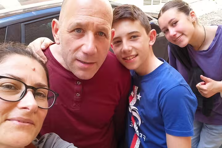 Happy family of four enjoying a guided medieval walking tour in Toledo, exploring ancient historic streets together.
