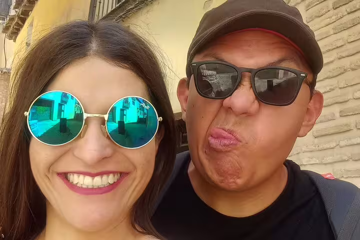 Cheerful couple taking a fun selfie on a guided walking tour through Toledo's medieval old town and historic lanes.