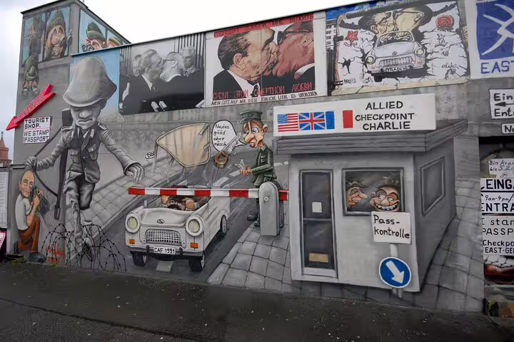 Colorful Checkpoint Charlie mural depicting Cold War Berlin Wall escape stories on a self-guided walking tour