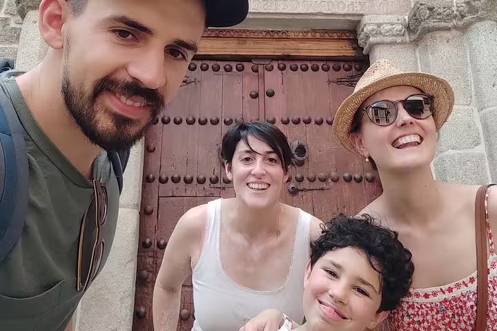 Smiling family posing before an ancient Toledo medieval door on a guided history and legends walking tour.