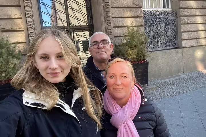 Family of three taking a selfie at a historic Berlin building during a self-guided Berlin Wall escape stories walking tour