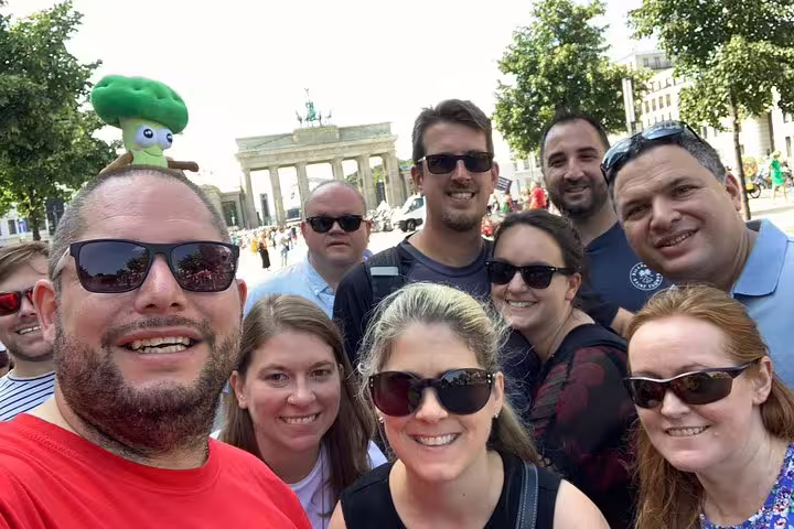 Happy group of tourists taking a selfie at Brandenburg Gate during Berlin Wall escape stories walking tour