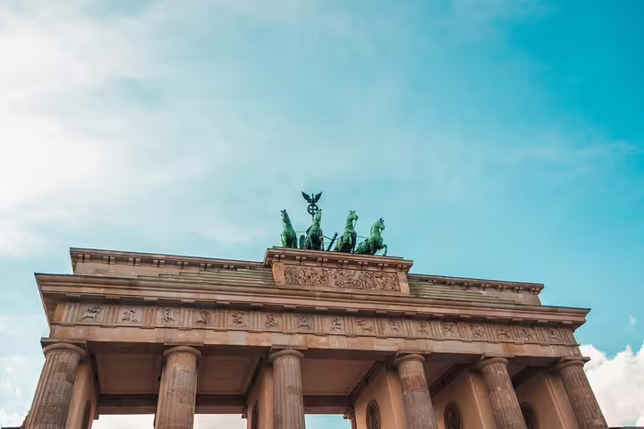 Iconic Brandenburg Gate with Quadriga statue against blue sky on Berlin Wall escape stories walking tour