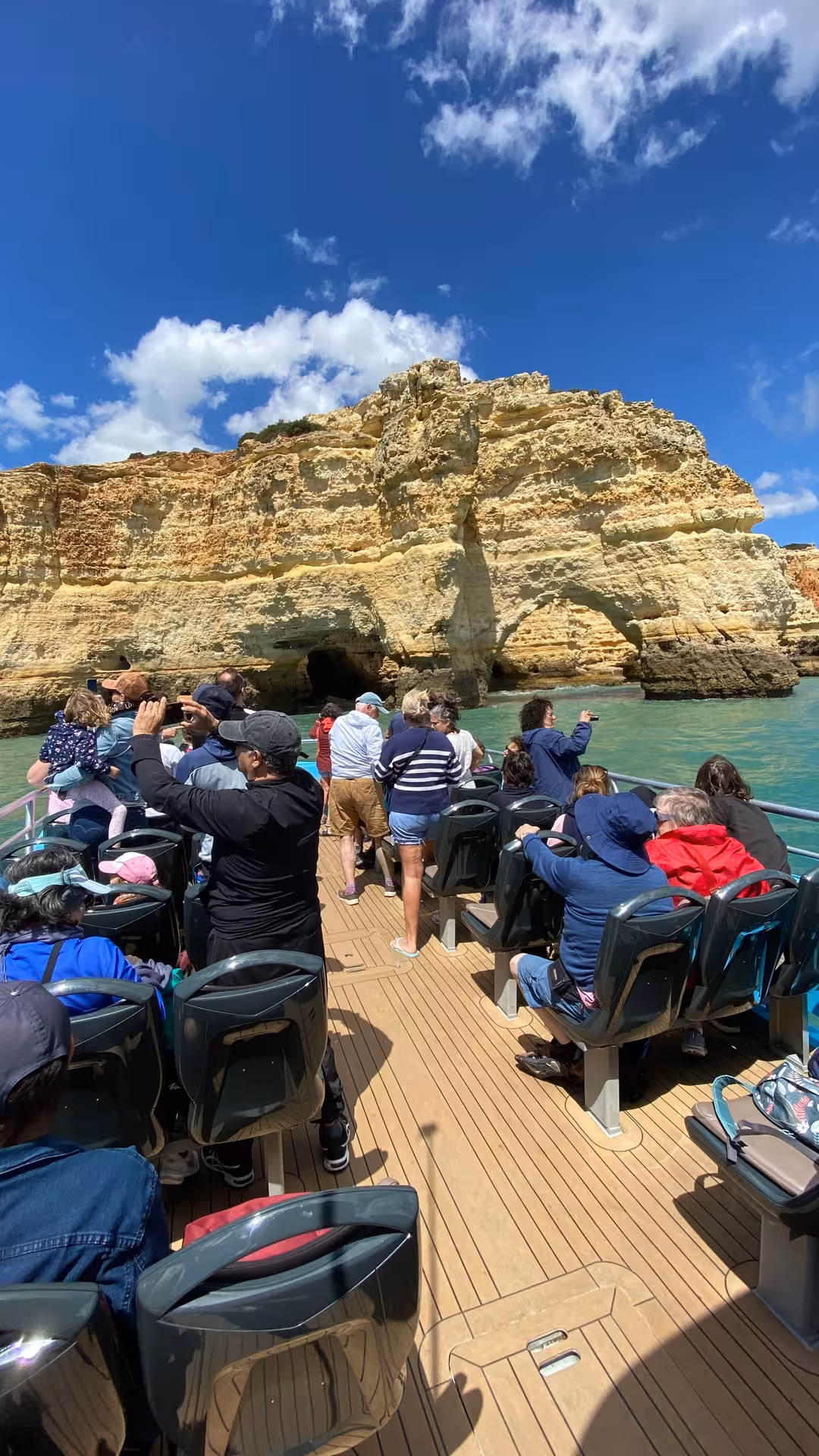 Tourists enjoy a scenic boat tour along the Algarve Coast, capturing the dramatic cliffs and caves.