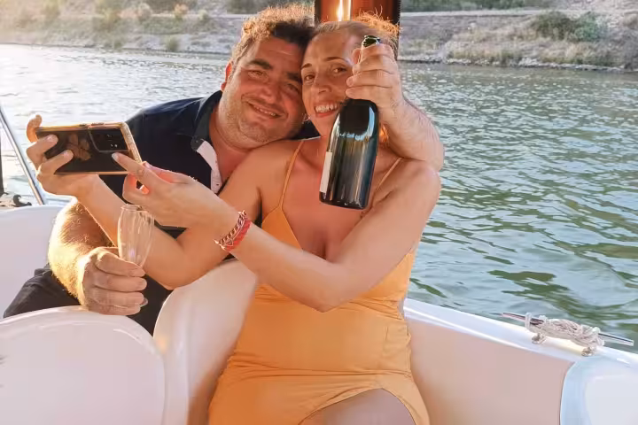 Happy couple enjoying port wine on a Douro River sunset boat tour from Pinhão, celebrating with sparkling wine