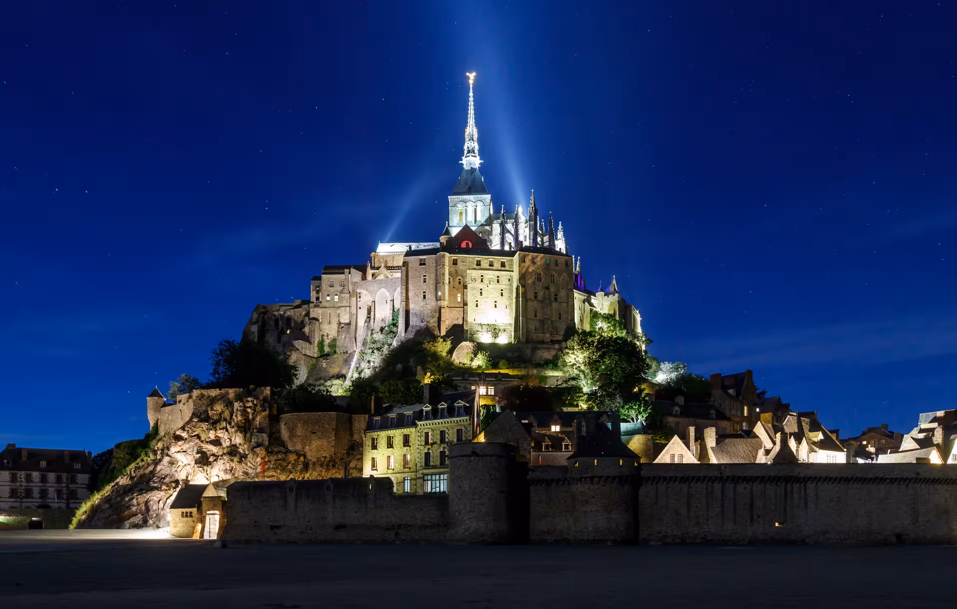 Mont Saint-Michel abbey illuminated at night, highlight of a private-style luxury minivan day trip, small group max 7