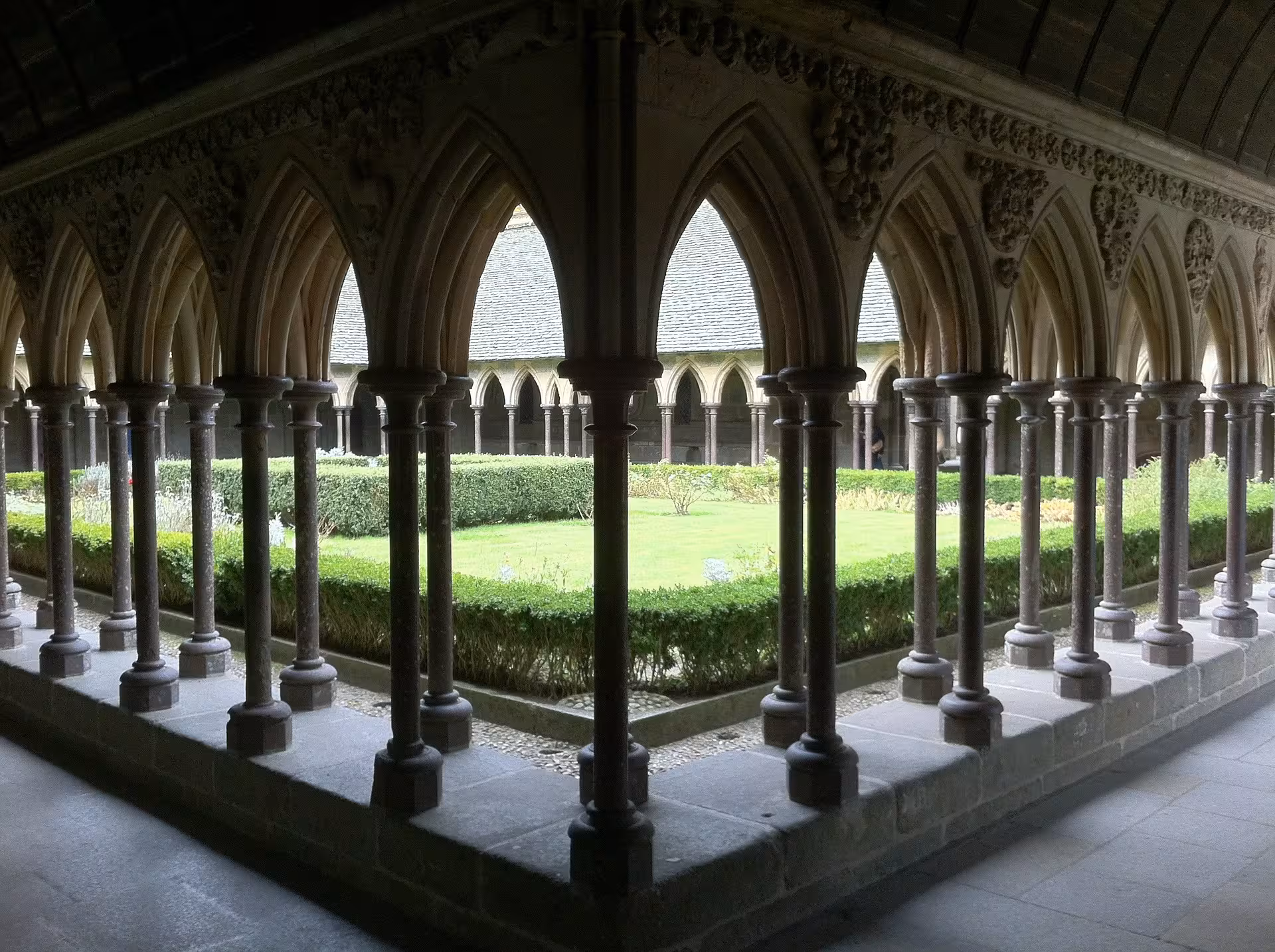 Gothic cloister arches and garden at Mont Saint-Michel Abbey, guided visit on customizable small-group tour