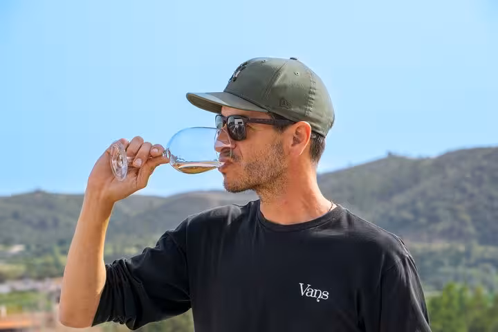 Man savoring white wine with scenic Silves hills backdrop on an Albufeira boutique winery tour and wine tasting experience