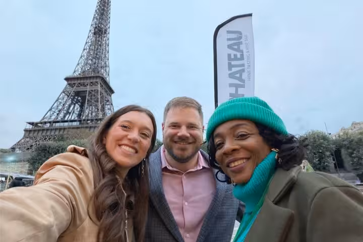 Guests smiling for a selfie by the Eiffel Tower before a Paris lunch or dinner dining experience upgrade