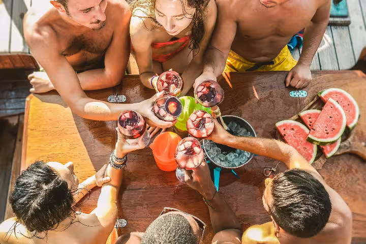 Friends toasting with sangria and fresh watermelon during a Lagos brunch boat tour near Ponta da Piedade
