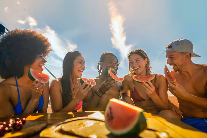 Friends enjoying fresh watermelon on a sunny Vilamoura brunch on board boat tour in the Algarve