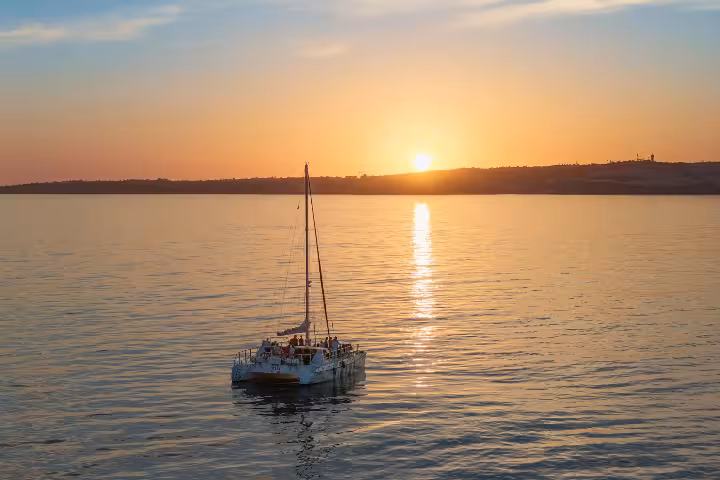Catamaran sailing on calm ocean waters during a breathtaking Portimao sunset experience tour in Algarve