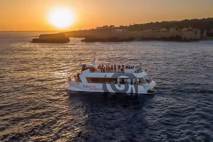 Aerial view of Espirito Oceanico catamaran sailing at golden sunset during Lagos sunset cruise tour Portugal.
