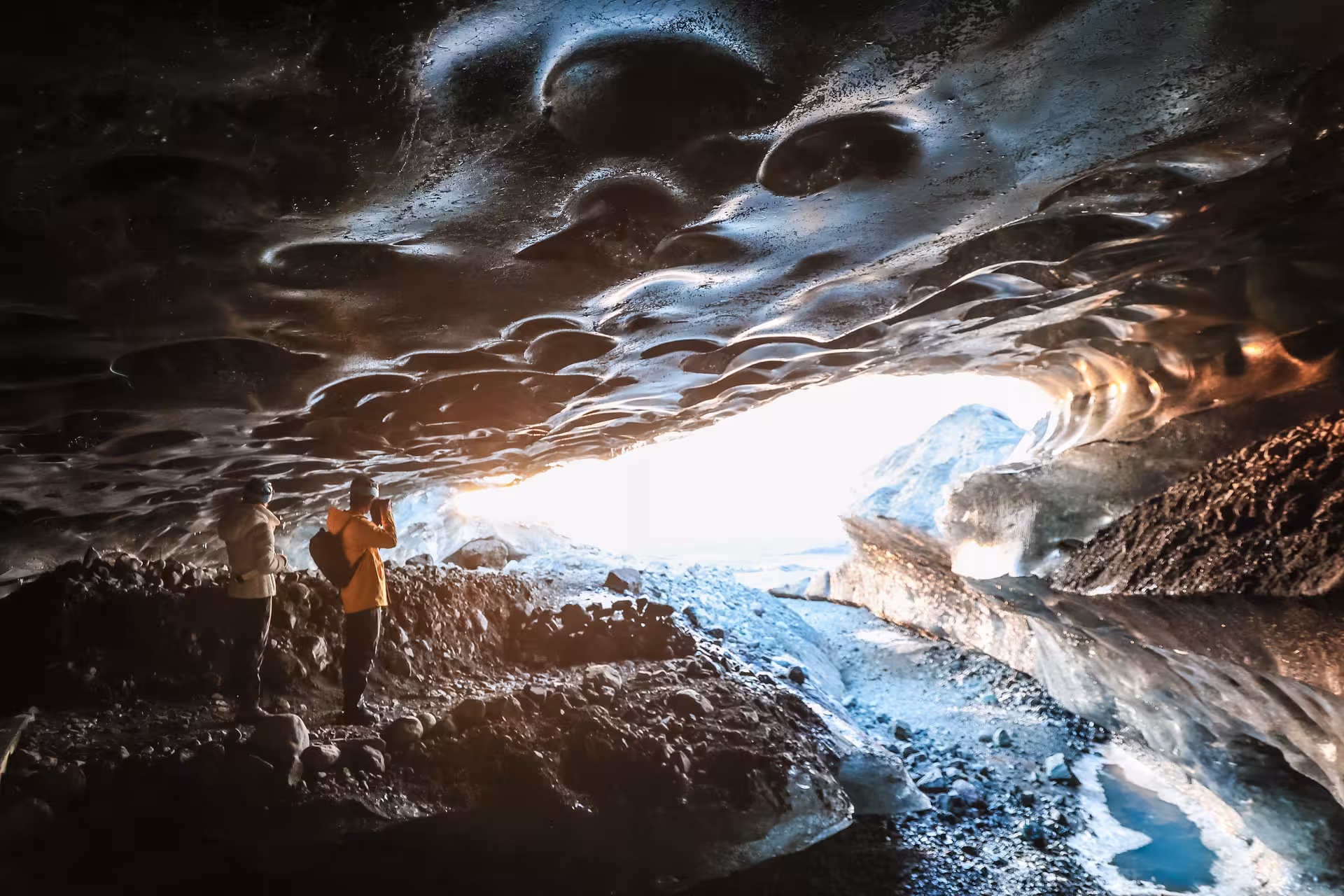 Two explorers photograph the stunning ice cave entrance on a Vatnajokull glacier guided tour in Iceland