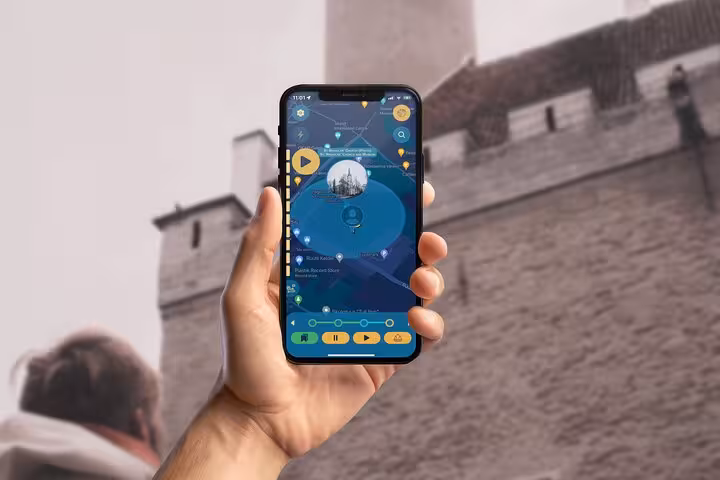 Hand holding smartphone displaying Tales of Reval GPS self-guided walking tour app with Tallinn landmarks map