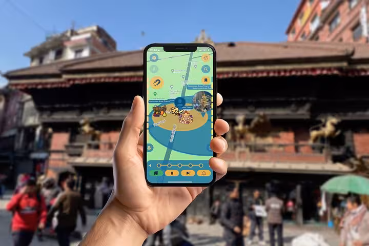 Hand holding a smartphone with GPS walking tour app at Kathmandu Durbar Square historic temples Nepal