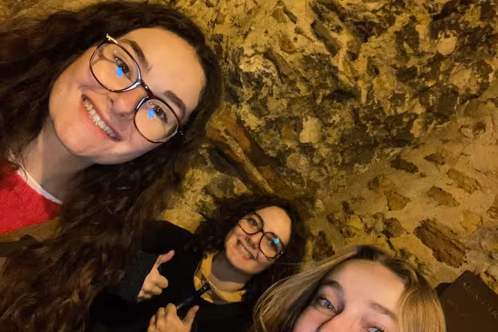 Three friends smiling in a dark stone tunnel during the Lyon haunted walking tour self-guided ghost hunt game.