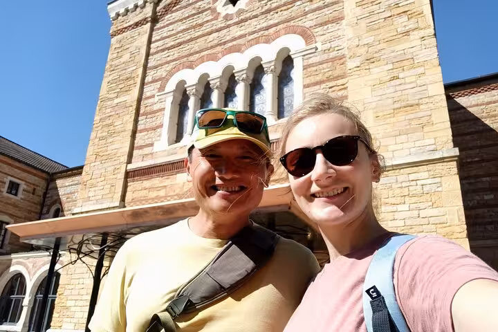 Two smiling tourists on a self-guided ghost hunt game tour posing in front of a historic stone building in Lyon