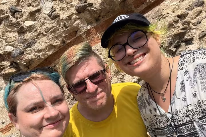 Three happy friends smiling beside an ancient stone wall during Lyon haunted self-guided ghost hunt walking tour