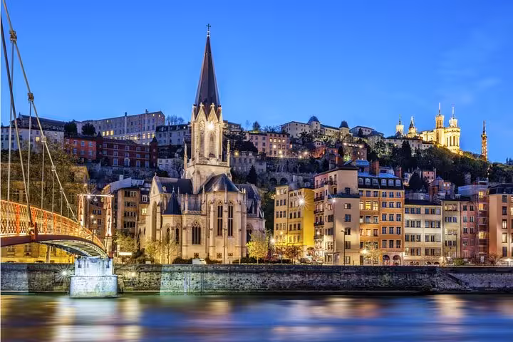 Lyon haunted walking tour featuring gothic church and Saône River at dusk with glowing city lights