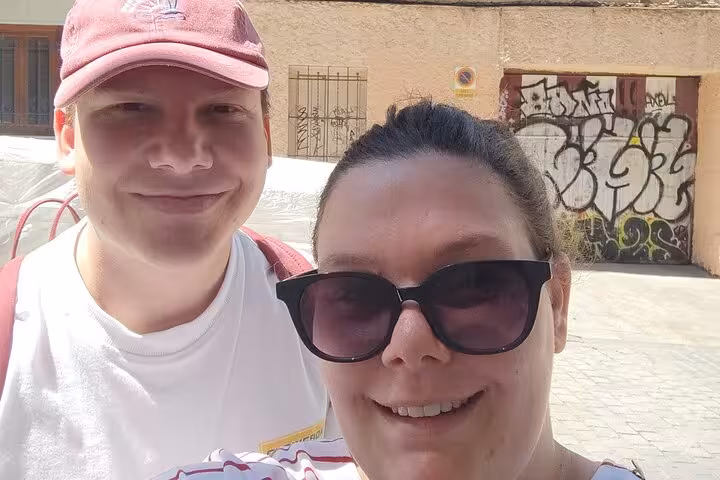 Smiling couple taking a selfie on a sunny Madrid street during the self-guided Escape the Inquisition walking tour.