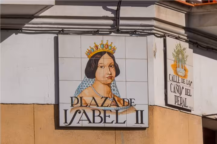 Colorful ceramic tile sign of Plaza de Isabel II in Madrid featuring Queen Isabella II on a historic street corner