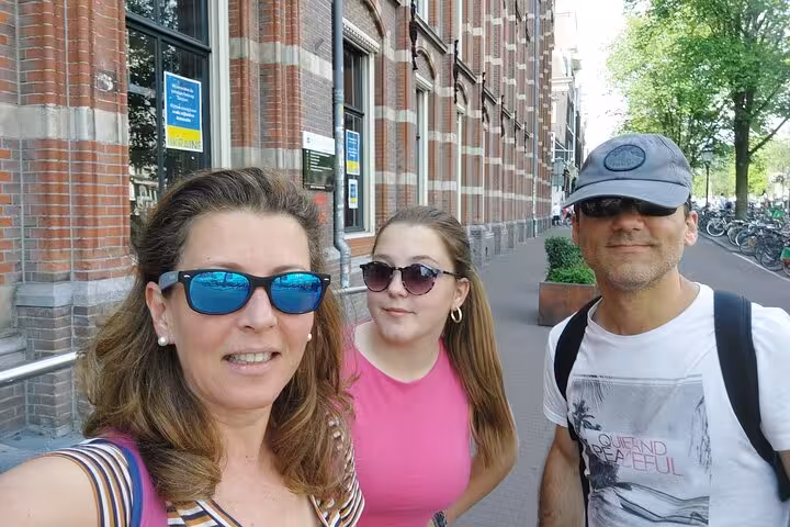 A happy family taking a selfie on a sunny Amsterdam street during a self-guided scavenger hunt tour.