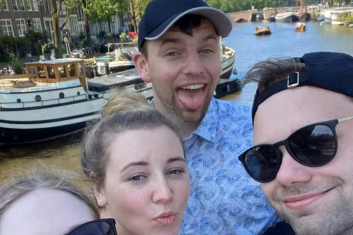 Excited group of friends taking a fun selfie by Amsterdam canal during a self-guided escape game scavenger hunt.