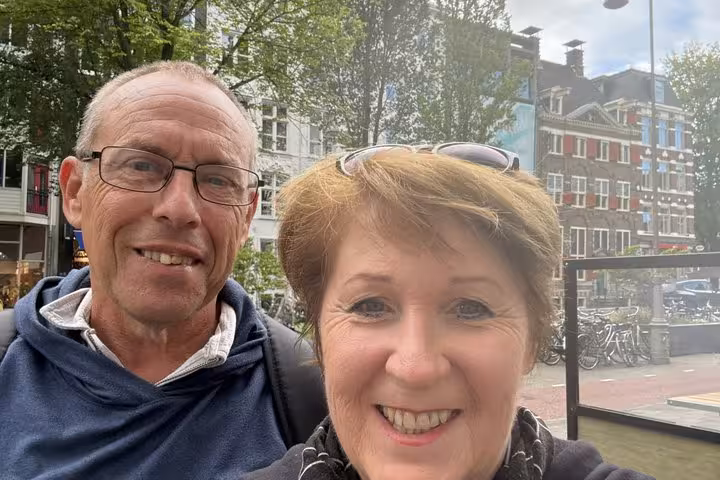 Happy couple taking a selfie in Amsterdam streets enjoying a fun self-guided escape game scavenger hunt tour