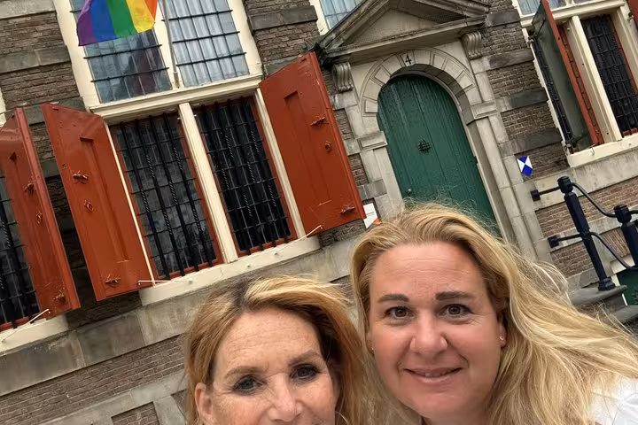 Two women smiling in front of a historic Amsterdam building during a fun self-guided scavenger hunt tour