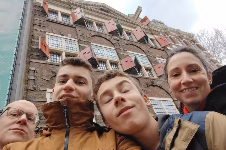 Happy family posing in front of iconic Amsterdam building enjoying a self-guided escape game scavenger hunt