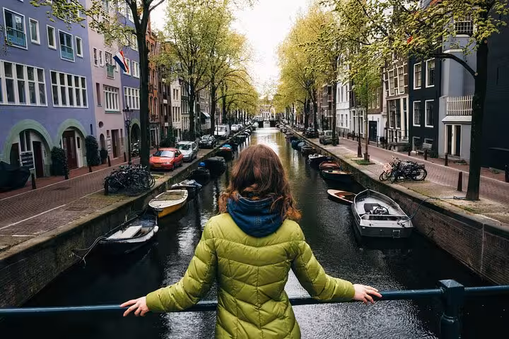 Woman in green jacket exploring Amsterdam canal on a self-guided escape game scavenger hunt adventure