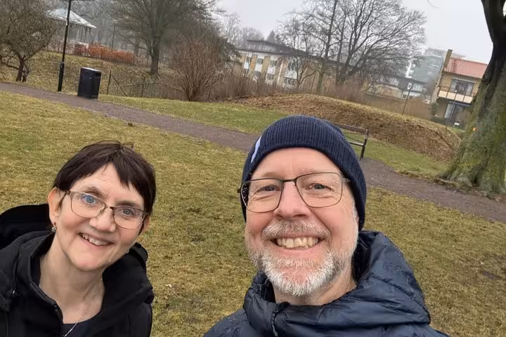Smiling couple enjoying a self-guided walking tour in Helsingborg Old Town park during a cloudy winter day
