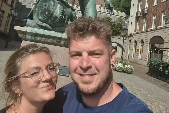 Couple smiling in selfie near bronze sculpture during self-guided walking tour in Helsingborg Old Town