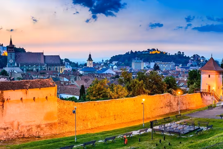 Stunning twilight panoramic view of medieval Brasov city walls and Black Church on a self-paced walking tour