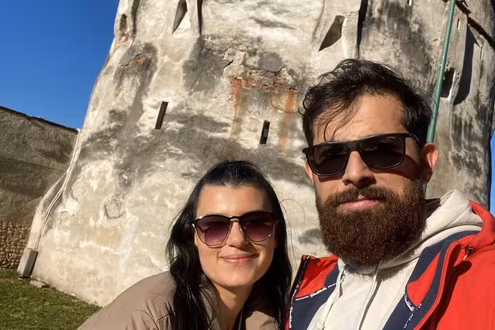 Couple posing beside an ancient medieval Brasov fortress tower during a fun self-paced walking game tour
