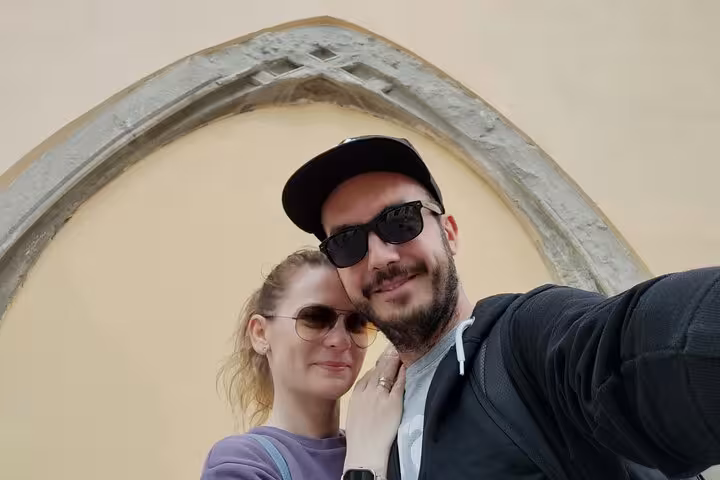 Couple posing under a medieval Gothic stone arch during a guided walking tour of historic Brasov Romania