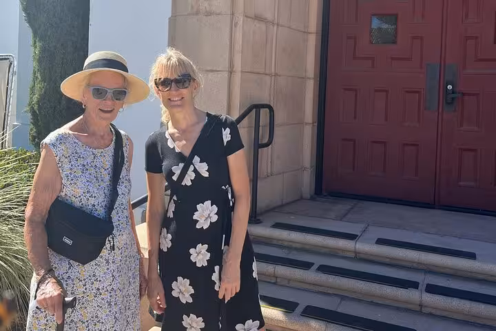 Two women smiling in front of a historic red-door building during a self-guided walking tour at Liberty Station San Diego
