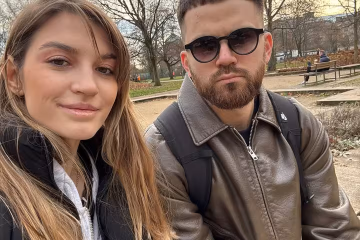 Couple enjoying a self-guided Berlin WW2 walking tour in a historic park using a smartphone app.