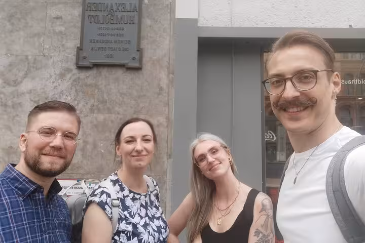 Group of friends posing by the Alexander von Humboldt plaque on a Berlin WW2 self-guided walking tour.