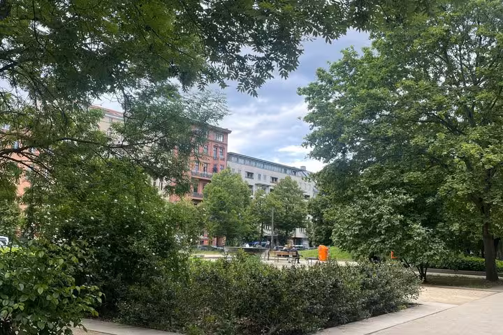 Lush green park in Berlin with historic buildings visible during a WW2 self-guided walking tour