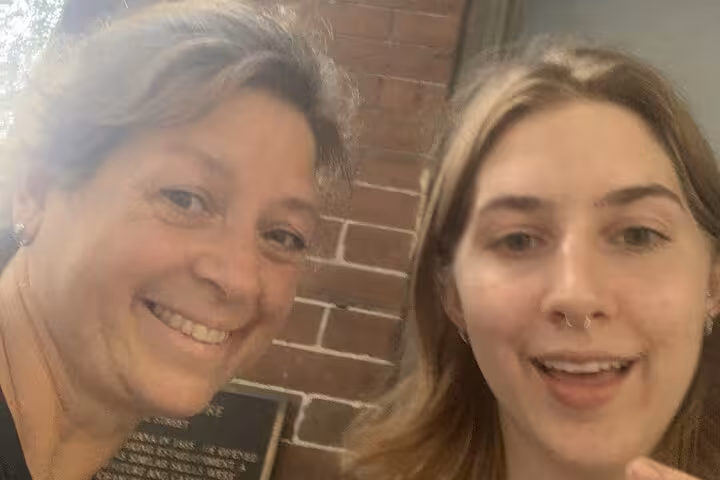 Two smiling women posing by a historic brick wall during a self-guided ghost hunt walking tour in Downtown Orlando.