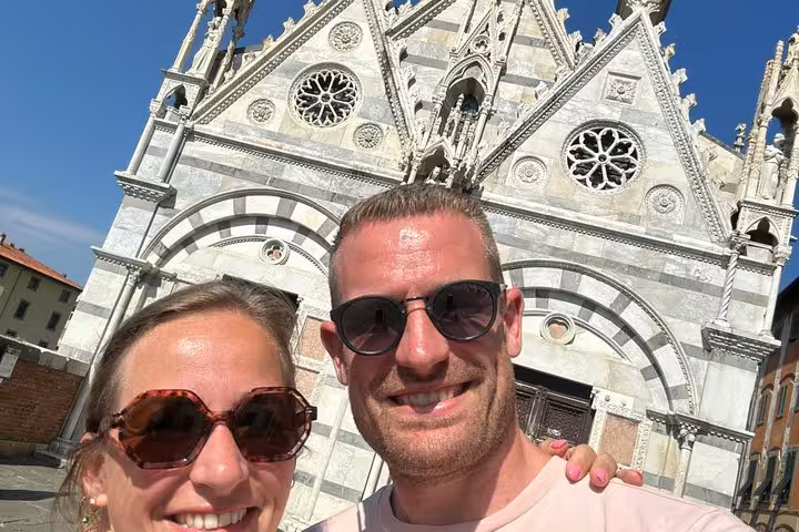 Happy couple smiling in front of Pisa cathedral during a self-guided mystery puzzle adventure tour