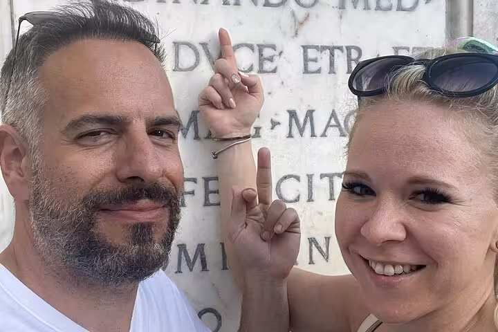 Couple decoding clues on a Latin inscription during Pisa self-guided mystery puzzle walking tour