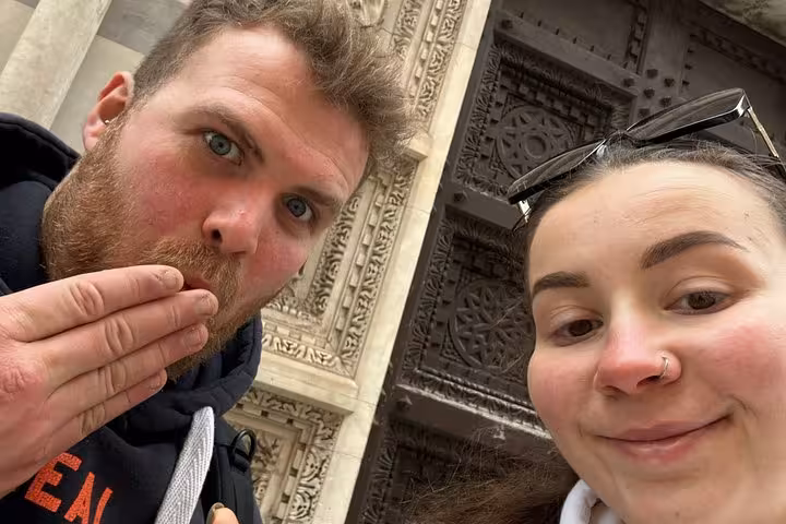 Couple taking fun selfie at ornate Pisa cathedral doorway during self-guided mystery puzzle adventure tour